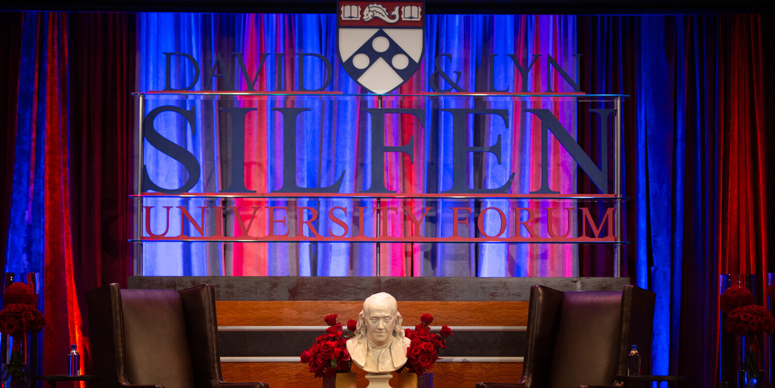 a stage with the Penn shield and Silfen Forum logo in front of curtains 